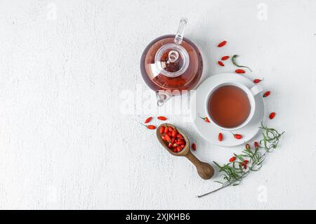 Tasse Kräuter-Goji-Beerentee mit frischen Goji-Beeren auf rustikalem Tisch Stockfoto