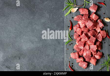 Gewürfeltes Rindfleisch auf Steinbrett mit Thymian und Paprika Stockfoto