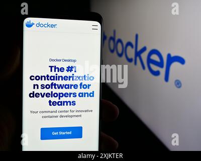 Person mit Mobiltelefon und Webseite des US-amerikanischen Produktivitätssoftware-Unternehmens Docker Inc. Vor dem Logo. Konzentrieren Sie sich auf die Mitte des Telefondisplays. Stockfoto