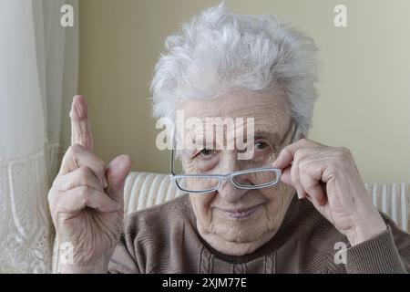 Eine alte Frau mit dem Finger nach oben, um sie zu ermahnen Stockfoto