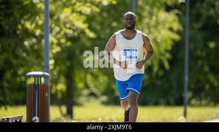 Porträt eines jungen schwarzen Joggers, der in einem Park auf einem Health Trail läuft. Gesunder und fitter afrikanischer Mann, der körperliche Aktivität genießt und in Form bleibt Stockfoto