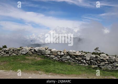 Blick auf eine Felswand, hinter der Morgennebel und weiße Wolken den Blick auf das Zillertal versperren Stockfoto