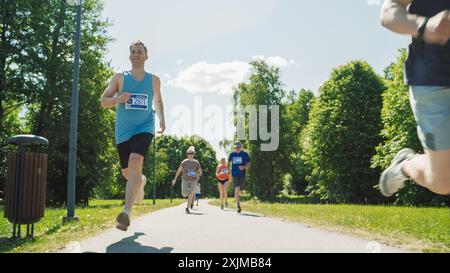 Porträt einer vielfältigen Gruppe von Menschen, die an einem Marathon teilnehmen und durch einen Park Trail laufen. Jogger, die sich lässig um den ersten Platz in einem Freundschaftsrennen bewerben Stockfoto