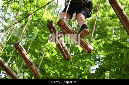 PRODUKTION - 19. Juli 2024, Hessen, Wiesbaden: Ein Jugendlicher kann auf einer Strecke im Kletterwald Neroberg hoch zielen. Der Kletterpark für junge und erfahrene Freizeitsportler liegt auf Wiesbadens Hausberg, umgeben von Buchen und Eichen. Der höchste Punkt ist ein Abenteuernest in einer Höhe von 25 Metern. Foto: Arne Dedert/dpa Stockfoto