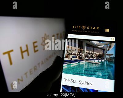 Stuttgart, Deutschland, 21.05.2022: Person, die ein Mobiltelefon hält, mit Webseite der Firma The Star Entertainment Group Limited auf dem Bildschirm mit Logo. Konzentrieren Sie sich auf Stockfoto