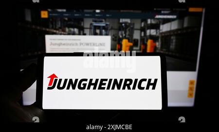 Stuttgart, 21.05.2022: Handybesitzer mit Logo des deutschen Maschinenbauunternehmens Jungheinrich AG auf dem Bildschirm vor dem Geschäft Stockfoto