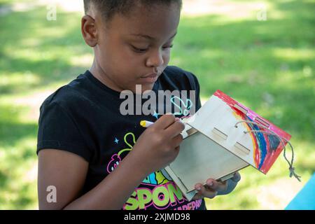 Detroit, Michigan - Ein Mädchen malt ein Vogelhaus, das sie beim jährlichen „Summer Sizzler“-Picknick und -Party von zwei Stadtteilen in Detroit zusammengestellt hat. Stockfoto