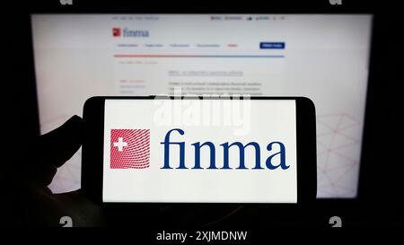 Stuttgart, Deutschland, 06.04.2022: Person mit Mobiltelefon mit Logo der Eidgenoessischen Finanzmarktaufsicht (FINMA) auf dem Bildschirm vor der Webseite. Stockfoto