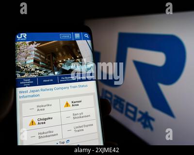 Stuttgart, Deutschland, 06.06.2022: Person, die ein Mobiltelefon hält, mit Webseite der japanischen Firma West Japan Railway (JR) auf dem Bildschirm vor dem Logo. Stockfoto