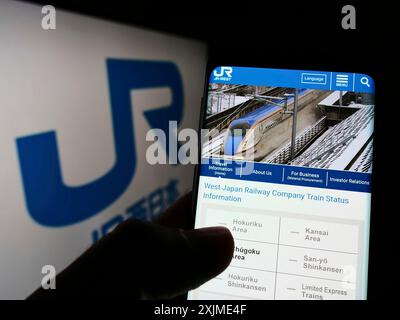 Stuttgart, Deutschland, 06.06.2022: Person, die ein Smartphone hält, mit Webseite der japanischen Firma West Japan Railway (JR) auf dem Bildschirm vor dem Logo. Fokus Stockfoto