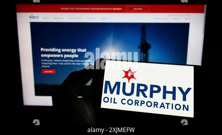 Stuttgart, Deutschland, 06.11.2022: Person, die ein Handy hält, mit dem Logo des amerikanischen Explorationsunternehmens Murphy Oil Corporation auf dem Bildschirm vor dem Bildschirm Stockfoto