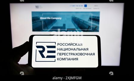 Stuttgart, Deutschland, 19.06.2022: Person mit Smartphone und Logo der russischen nationalen Rückversicherungsgesellschaft (RNRC) auf dem Bildschirm vor der Website. Stockfoto