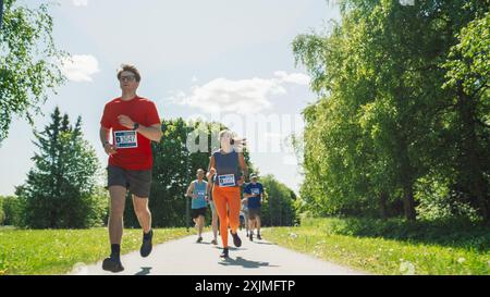 Porträt einer vielfältigen Gruppe von Menschen, die an einem Marathon teilnehmen und durch einen Park Trail laufen. Jogger, die sich lässig um den ersten Platz in einem Freundschaftsrennen bewerben Stockfoto