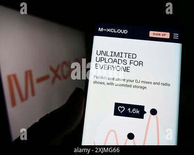 Stuttgart, Deutschland, 07.03.2022: Person, die ein Mobiltelefon hält, mit Webseite des britischen Musikstreamingunternehmens Mixcloud Limited auf dem Bildschirm mit Logo. Fokus Stockfoto