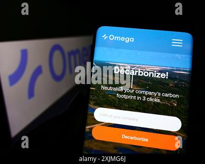 Stuttgart, Deutschland, 07.03.2022: Person mit Smartphone mit Website des brasilianischen Erneuerbare-Energien-Unternehmens Omega Energia auf dem Bildschirm mit Logo. Fokus Stockfoto