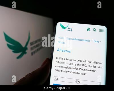 Stuttgart, Deutschland, 07-10-2022: Person, die ein Smartphone hält, mit Webseite der Hong Kong Securities and Futures Commission (SFC) auf dem Bildschirm mit Logo. Stockfoto