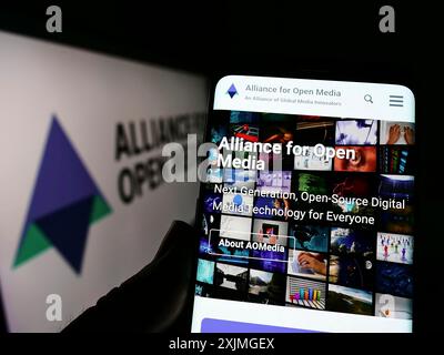 Stuttgart, Deutschland, 07.10.2022: Person, die ein Mobiltelefon hält, mit Webseite des Konsortiums Alliance for Open Media (AOMedia) auf dem Bildschirm mit Logo. Konzentrieren Sie sich auf Stockfoto