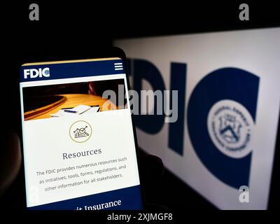 Stuttgart, Deutschland, 07-10-2022: Person, die ein Mobiltelefon hält, mit Webseite der US Federal Deposit Insurance Corporation (FDIC) auf dem Bildschirm mit Logo. Fokus Stockfoto