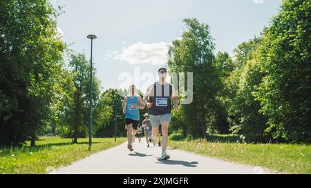 Porträt einer Gruppe von Personen, die gemeinsam an einem Marathon teilnehmen und durch einen Park Trail laufen. Jogger geben ihr Bestes, um die Ziellinie in einem freundlichen Rennen zu erreichen Stockfoto