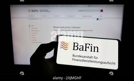 Stuttgart, 15.07.2022: Person mit Handy mit Logo der deutschen Finanzaufsichtsbehörde BaFin auf dem Bildschirm vor der Webseite. Stockfoto