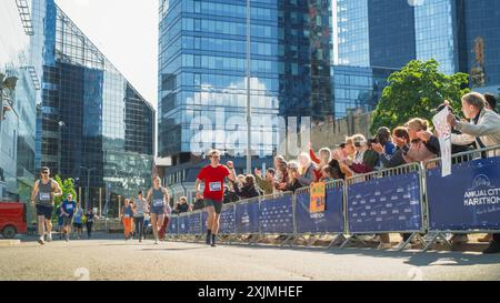 Verschiedene Gruppen von Menschen, die an einem Marathon-Rennen in der Stadt teilnehmen. Familie und Freunde im Publikum jubeln begeistert und unterstützen ihre Lieben Stockfoto