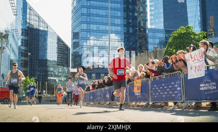 Verschiedene Gruppen von Menschen, die an einem Marathon-Rennen in der Stadt teilnehmen. Familie und Freunde im Publikum jubeln begeistert und unterstützen ihre Lieben Stockfoto