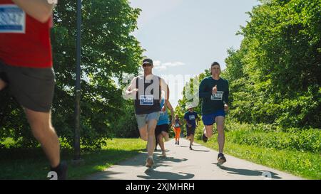 Porträt einer Gruppe von Personen, die gemeinsam an einem Marathon teilnehmen und durch einen Park Trail laufen. Jogger geben ihr Bestes, um die Ziellinie in einem freundlichen Rennen zu erreichen Stockfoto