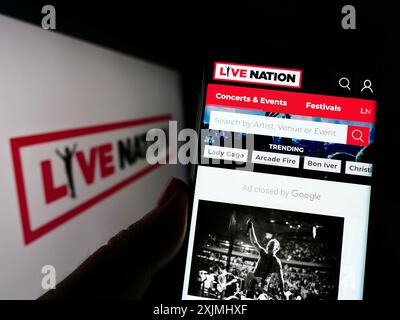 Stuttgart, 24.07.2022: Person, die eine Zellphnoe hält, mit Webseite der US-amerikanischen Firma Live Nation Entertainment Inc. Vor dem Logo auf dem Bildschirm. Fokus Stockfoto