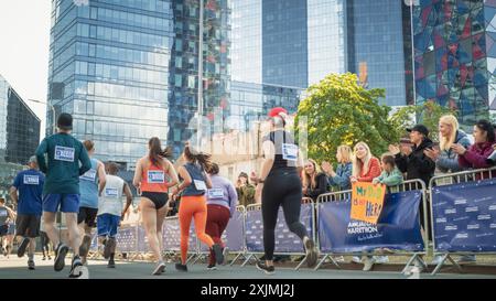 Rückansicht: Verschiedene Marathon-Jogger, die um den ersten Platz kämpfen, auf einem City Trail laufen, Publikum klatschen und ihre Lieben bejubeln, die am Rennen teilnehmen Stockfoto