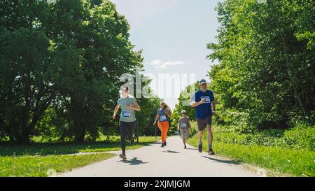 Porträt einer Gruppe von Personen, die gemeinsam an einem Marathon teilnehmen und durch einen Park Trail laufen. Jogger geben ihr Bestes, um die Ziellinie in einem freundlichen Rennen zu erreichen Stockfoto