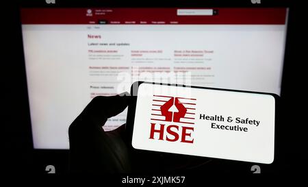 Stuttgart, Deutschland, 07-31-2022: Person mit Mobiltelefon mit Logo der britischen Agentur Health and Safety Executive (HSE) auf dem Bildschirm vor der Webseite. Stockfoto