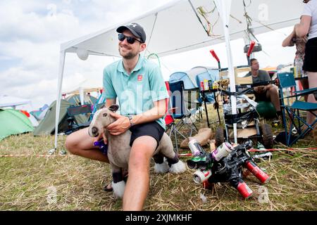 Nordholz, Deutschland. Juli 2024. Festivalbesucher Christian sitzt auf einem Stoffpferd, das er mit auf den Campingplatz Deichbrand Festival mitgebracht hat. Das Open-Air-Festival mit rund 60.000 Besuchern findet vom 18. Bis 21. Juli statt. Quelle: Hauke-Christian Dittrich/dpa/Alamy Live News Stockfoto