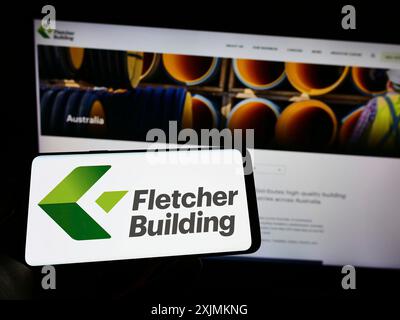 Stuttgart, Deutschland, 09.04.2022: Person, die ein Mobiltelefon mit dem Logo des Bauunternehmens Fletcher Building Limited auf dem Bildschirm vor der Webseite hält. Stockfoto