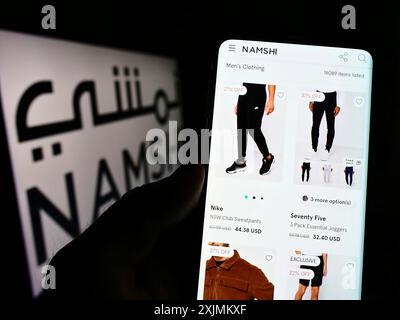 Stuttgart, 28.08.2022: Person, die ein Mobiltelefon hält, mit Webseite des arabischen E-Commerce-Unternehmens Namshi vor dem Firmenlogo. Fokus Stockfoto