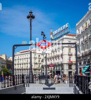 Schild der U-Bahn-Station Sol an einem sonnigen Tag, mit dem Neonschild Tio Pepe im Hintergrund. Puerta del Sol, Madrid, Spanien Stockfoto