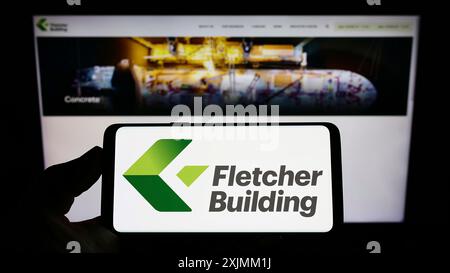 Stuttgart, Deutschland, 09.04.2022: Person, die ein Smartphone mit dem Logo des Bauunternehmens Fletcher Building Limited auf dem Bildschirm vor der Website hält. Stockfoto