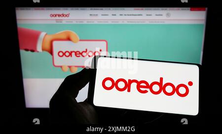 Stuttgart, Deutschland, 09.07.2022: Person, die ein Mobiltelefon mit dem Logo des katarischen Telekommunikationsunternehmens Ooredoo QSC auf dem Bildschirm vor der Webseite hält. Stockfoto