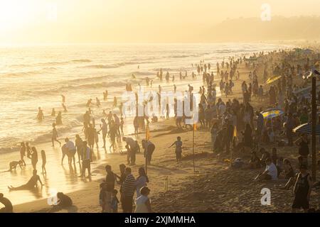 Touristen in Silhouette schwimmen und spielen im Pazifik am Santa Monica Beach in der Nähe von Los Angeles, Kalifornien, zur goldenen Stunde an einem trüben Tag Stockfoto