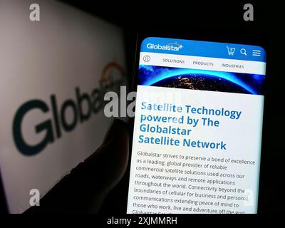 Stuttgart, Deutschland, 09.10.2022: Person, die ein Mobiltelefon hält, mit der Webseite des Satellitenkommunikationsunternehmens Globalstar Inc. Auf dem Bildschirm mit Logo. Fokus Stockfoto