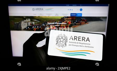 Stuttgart, Deutschland, 09-30-2022: Person, die ein Mobiltelefon mit dem Logo der italienischen Regulierungsbehörde ARERA auf dem Bildschirm vor der Weite hält. Konzentrieren Sie sich auf das Telefon Stockfoto