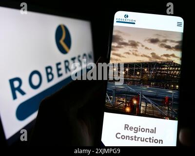 Stuttgart, Deutschland, 25.09.2022: Person, die ein Smartphone hält, mit Website des Bauunternehmens Robertson Group Limited auf dem Bildschirm mit Logo. Konzentrieren Sie sich auf Stockfoto