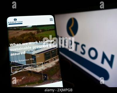 Stuttgart, 25.09.2022: Person, die ein Mobiltelefon hält, mit Webseite des Bauunternehmens Robertson Group Limited auf dem Bildschirm mit Logo. Konzentrieren Sie sich auf Stockfoto
