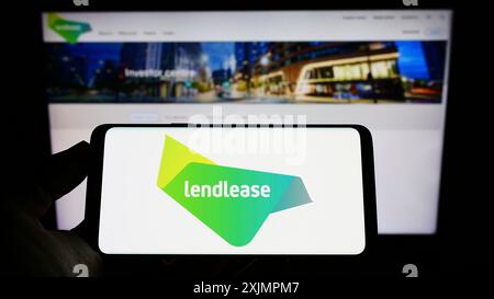Stuttgart, Deutschland, 10.01.2022: Person, die ein Mobiltelefon hält, mit dem Logo der Immobiliengesellschaft Lendlease Corporation Limited auf dem Bildschirm vor dem Bildschirm Stockfoto