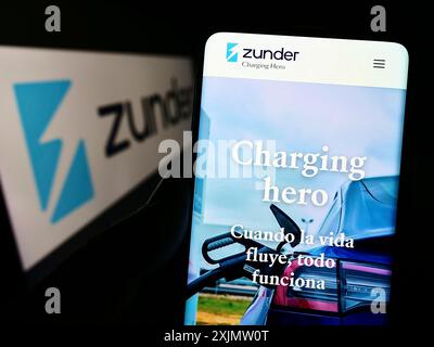 Stuttgart, 23.10.2022: Person, die ein Mobiltelefon hält, mit Webseite des spanischen Unternehmens Grupo Easycharger sl (Zunder) auf dem Bildschirm mit Logo. Konzentrieren Sie sich auf Stockfoto