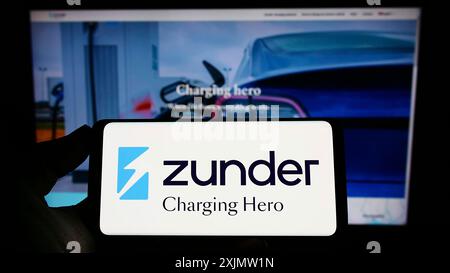 Stuttgart, 23.10.2022: Person, die ein Mobiltelefon mit dem Logo der spanischen Firma Grupo Easycharger sl (Zunder) auf dem Bildschirm vor der Webseite hält. Stockfoto