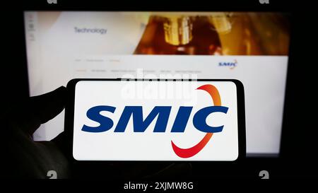 Stuttgart, Deutschland, 11-30-2022: Person, die ein Mobiltelefon mit dem Logo der Semiconductor Manufacturing International Corp. (SMIC) auf dem Bildschirm und auf der Webseite hält. Stockfoto