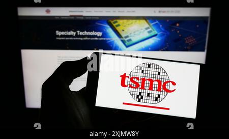 Stuttgart, Deutschland, 11-30-2022: Person, die ein Mobiltelefon mit dem Logo der Taiwan Semiconductor Manufacturing Company (TSMC) auf dem Bildschirm hält Stockfoto