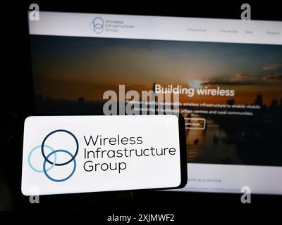 Stuttgart, Deutschland, 12.01.2022: Person, die ein Smartphone mit dem Logo der Wireless Infrastructure Group (WIG) auf dem Bildschirm vor der Website hält. Stockfoto