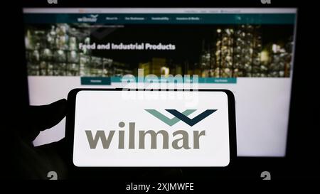 Stuttgart, Deutschland, 12.02.2022: Person, die ein Smartphone mit dem Logo des singapurischen Unternehmens Wilmar International Limited auf dem Bildschirm hält Stockfoto