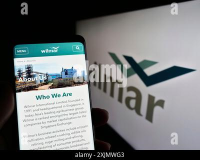 Stuttgart, Deutschland, 12.02.2022: Person, die ein Mobiltelefon hält, mit Website des singapurischen Unternehmens Wilmar International Limited auf dem Bildschirm mit Logo. Fokus Stockfoto
